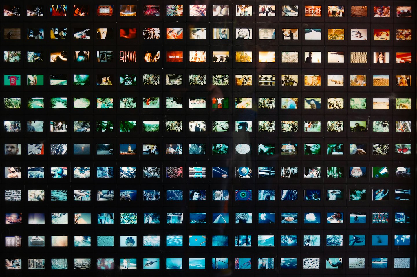 Grid of backlit slide transparencies glowing on a wall.