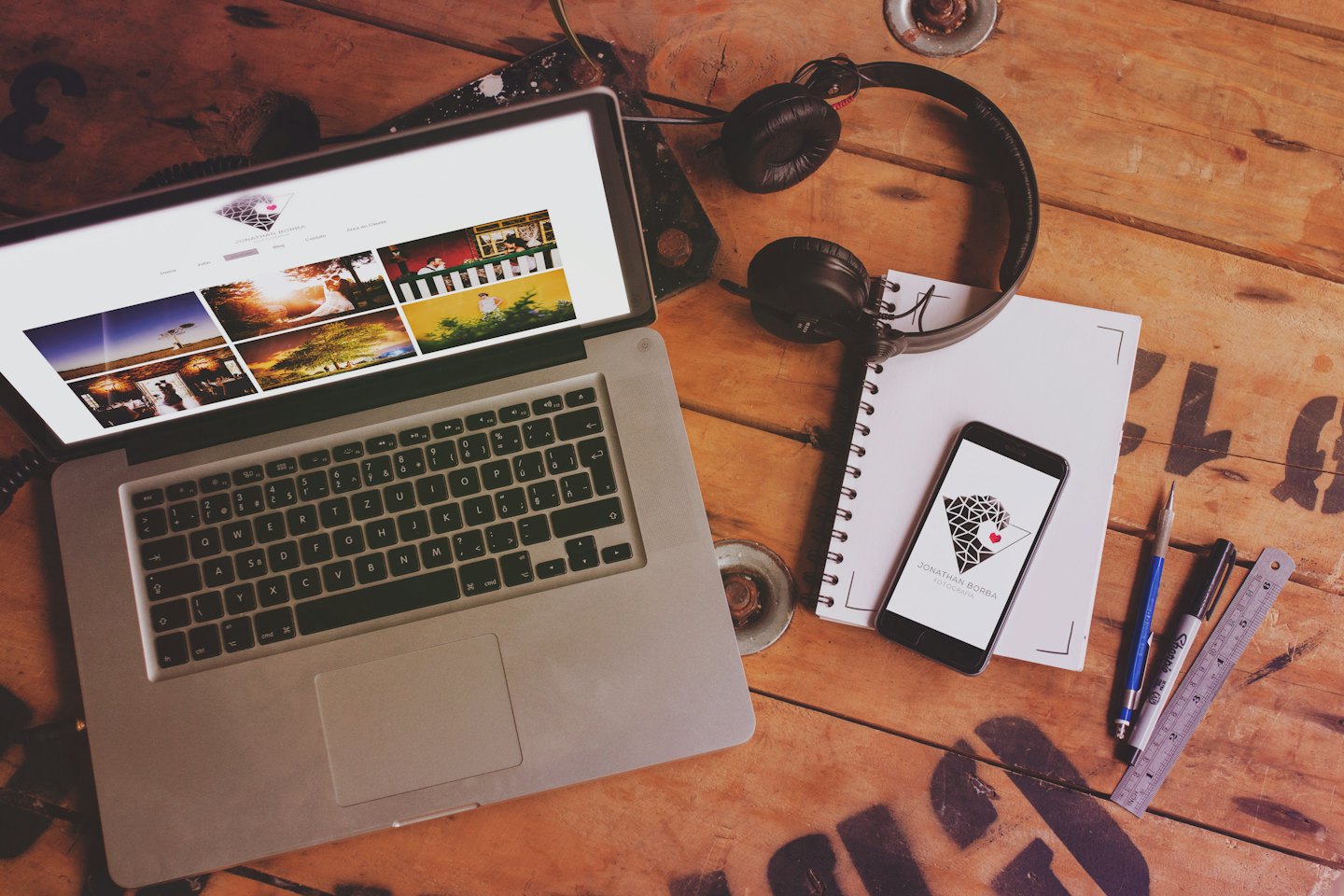 Laptop, headphones, and notebook on a wooden desk.